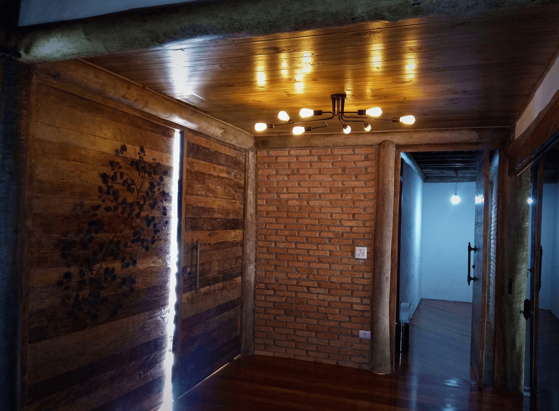 No Hall de Entrada da casa rústica a modernidade e o bom gosto se aliam. A combinação da madeira de demolição, usada na porta de Entrada e no assoalho, com o eucalipto roliço, usado na Estrutura, traz requinte e sustentabilidade para o projeto.