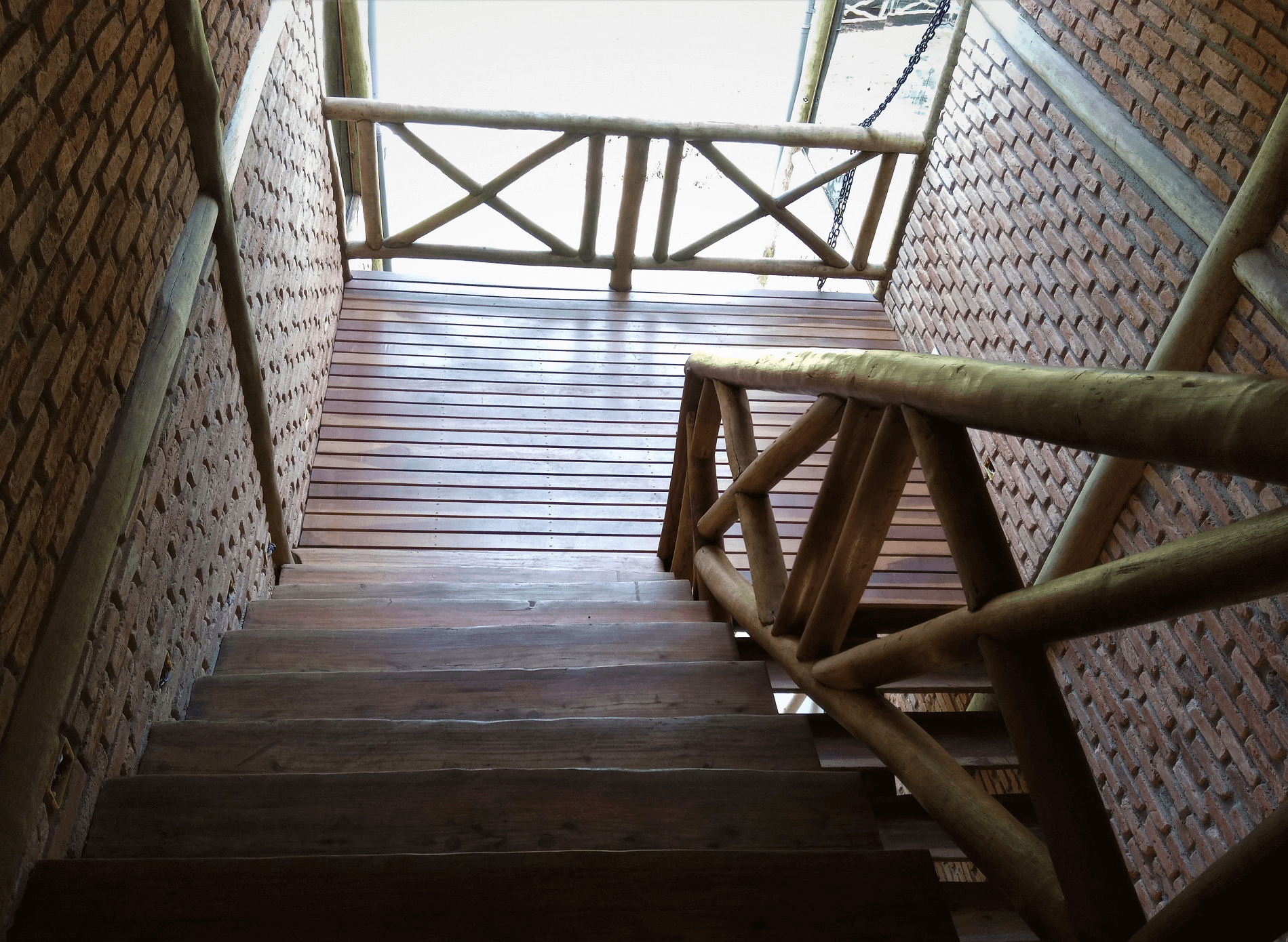 Os acessos internos entre os pavimentos são feitos pelas escadas confeccionadas com ½ cana de eucalipto tratado. No corrimão foi usado eucalipto tratado e nos patamares de descanso, deck de Cumaru. A caixa da escada recebeu vidros e paredes de tijolo de demolição.